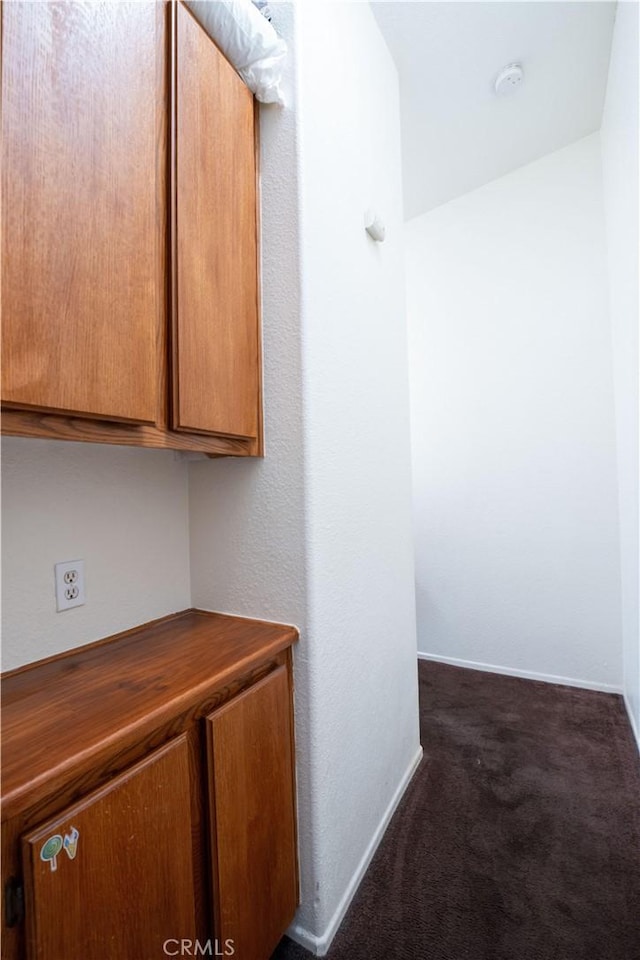 corridor featuring baseboards and carpet floors