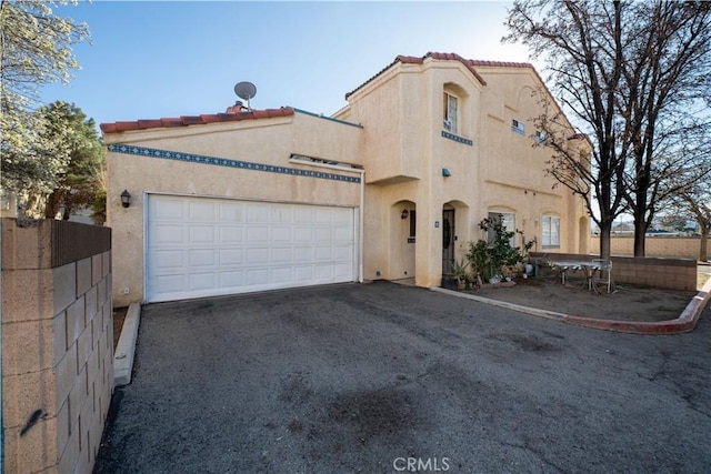 mediterranean / spanish-style house with fence, a garage, and stucco siding