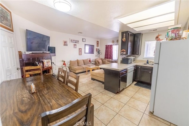 kitchen with white appliances, a peninsula, light tile patterned flooring, light countertops, and open floor plan