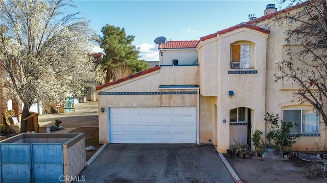 mediterranean / spanish-style house featuring stucco siding, driveway, a tile roof, and a garage