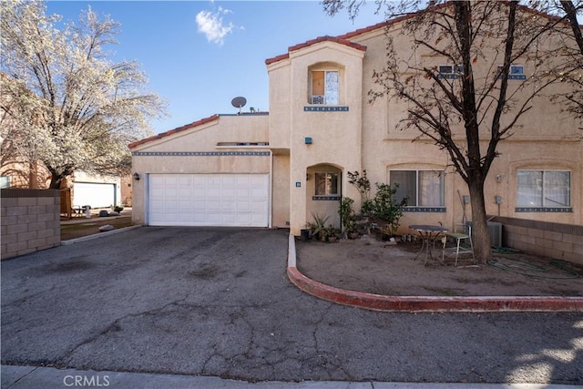 view of front of property with stucco siding, driveway, a tile roof, and a garage