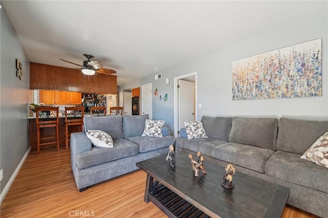 living area with ceiling fan, visible vents, baseboards, and light wood-style flooring