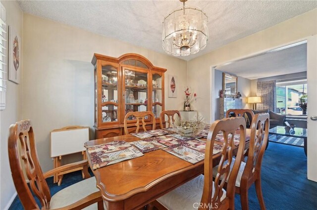 dining area featuring a textured ceiling, carpet, and a chandelier