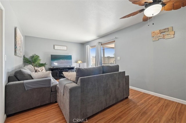 living area with baseboards, a ceiling fan, and light wood finished floors