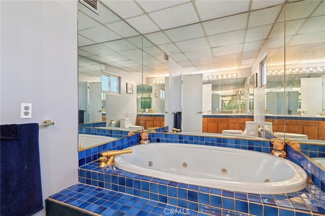 bathroom featuring visible vents, a jetted tub, a drop ceiling, toilet, and vanity