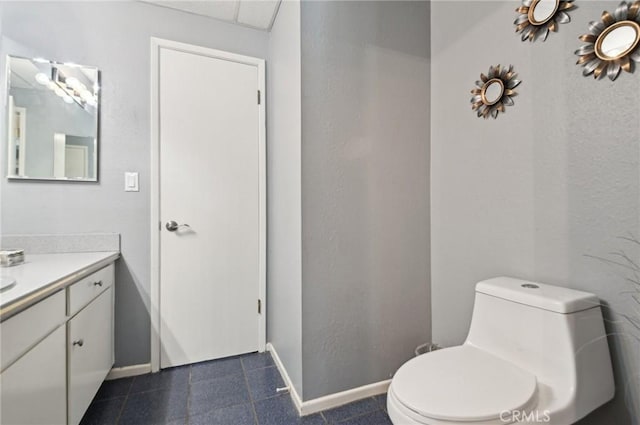 bathroom with tile patterned flooring, toilet, vanity, and baseboards