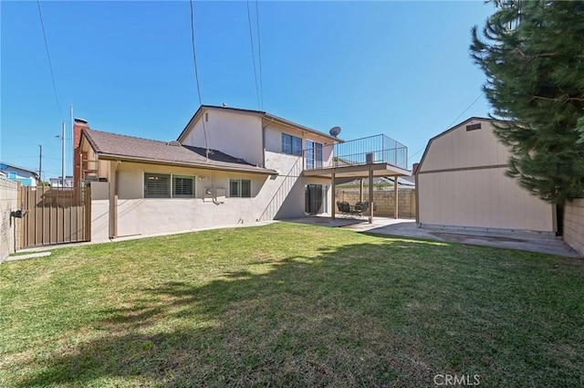 back of property featuring fence, stucco siding, a lawn, an outdoor structure, and a patio area