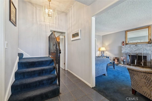 stairs with an inviting chandelier, a fireplace, a textured ceiling, and baseboards