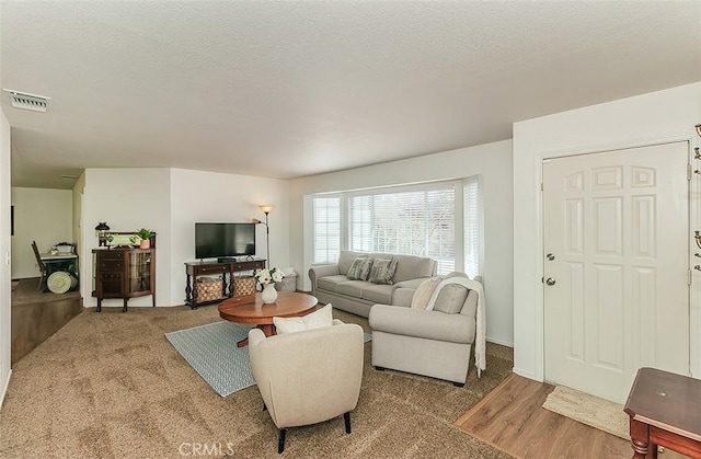 living room with visible vents, a textured ceiling, and wood finished floors