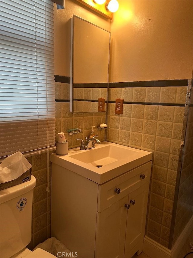 bathroom with vanity, tile walls, and toilet