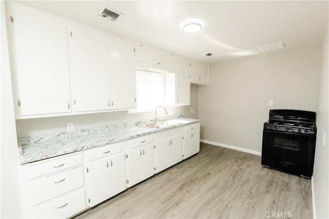 kitchen featuring light wood-style flooring, black gas range oven, visible vents, and a sink