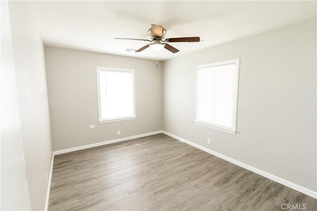 empty room featuring baseboards, wood finished floors, and a ceiling fan