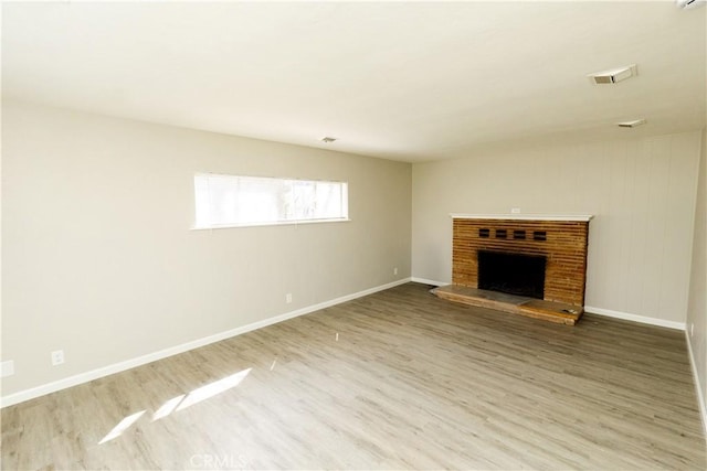 unfurnished living room featuring baseboards, wood finished floors, and a fireplace