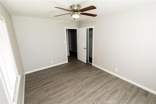 spare room featuring ceiling fan, a wealth of natural light, baseboards, and wood finished floors