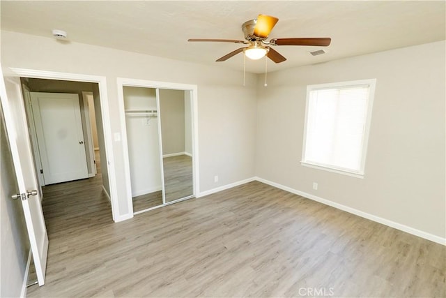 unfurnished bedroom featuring a closet, ceiling fan, baseboards, and light wood-style floors