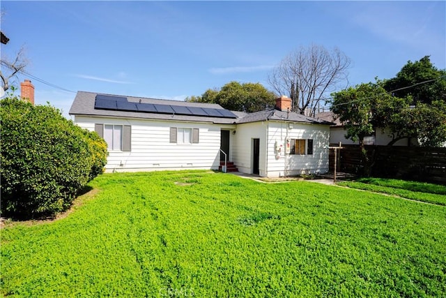 rear view of house featuring a yard, solar panels, and entry steps