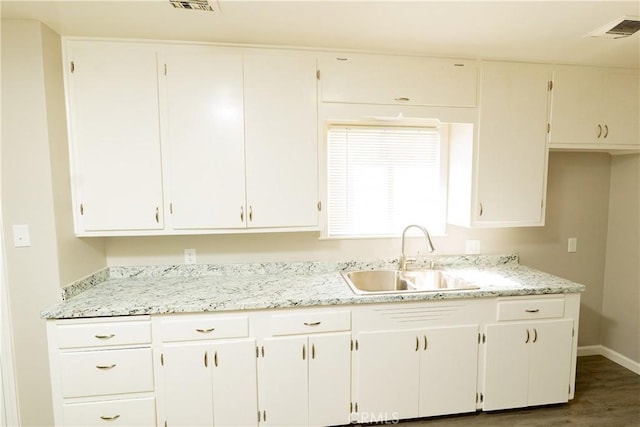 kitchen featuring a sink, visible vents, baseboards, and white cabinets