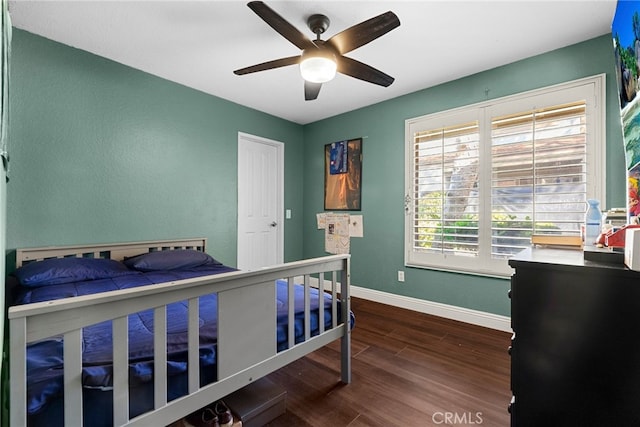 bedroom featuring baseboards, ceiling fan, and dark wood-style flooring