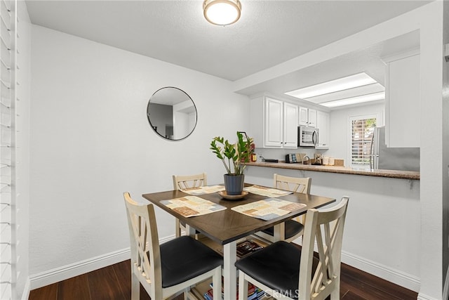 dining area featuring baseboards and dark wood-type flooring