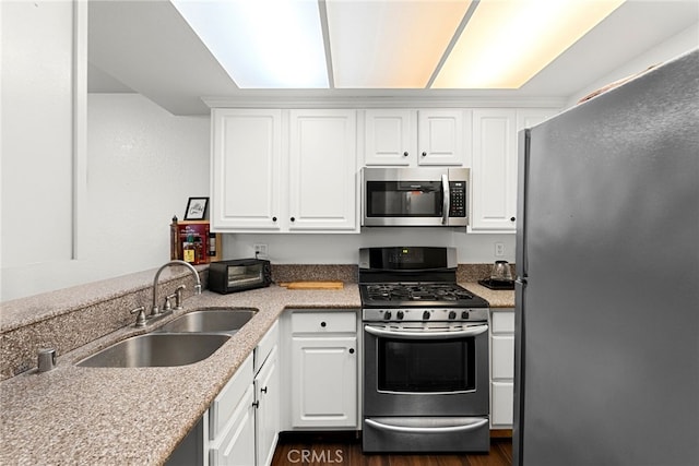 kitchen with a sink, dark wood-style floors, appliances with stainless steel finishes, and white cabinets