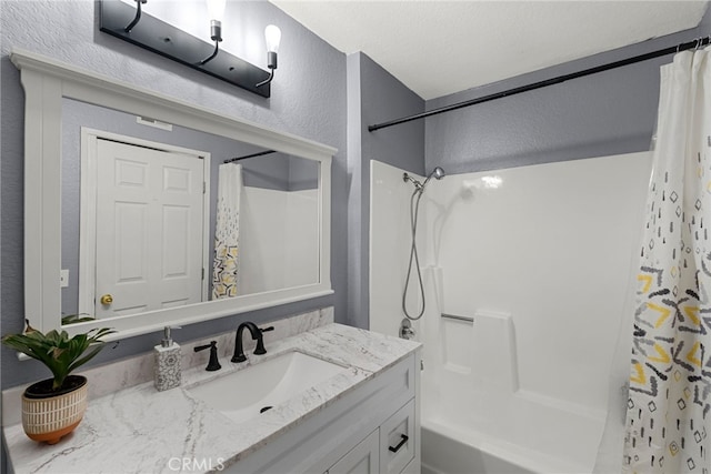 bathroom with shower / bathtub combination with curtain, vanity, and a textured wall