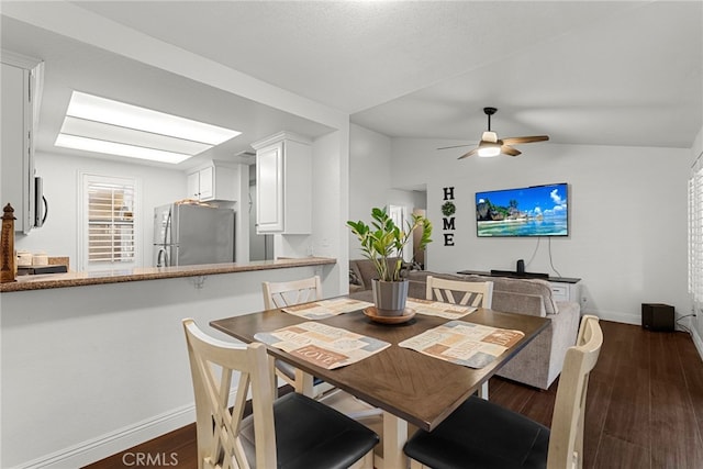 dining space featuring dark wood-style floors, ceiling fan, baseboards, and lofted ceiling