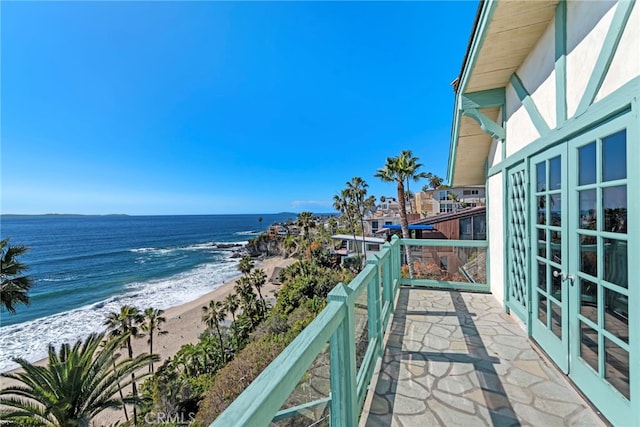balcony featuring french doors and view of water and beach