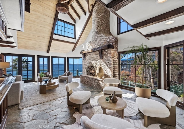 interior space featuring a brick fireplace, beamed ceiling, wood ceiling, stone finish floor, and high vaulted ceiling