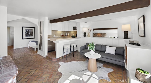 living room featuring brick floors and beamed ceiling
