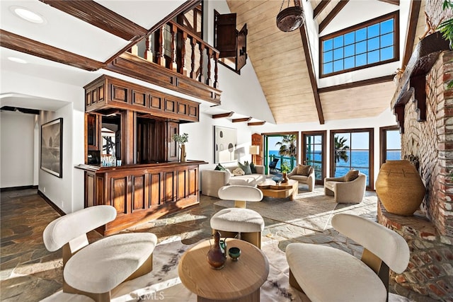 living area featuring beam ceiling, dark stone finish floors, high vaulted ceiling, baseboards, and a water view