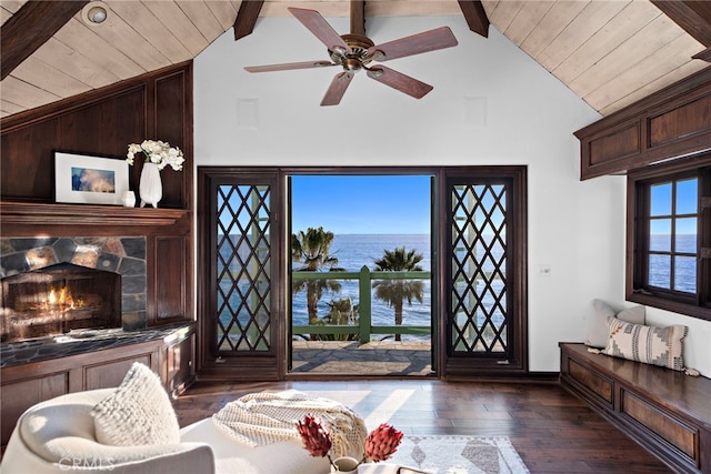 living area featuring a water view, wood ceiling, dark wood-style floors, a tiled fireplace, and baseboards