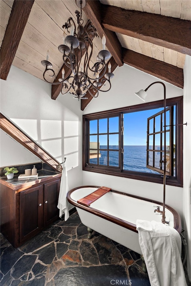 bathroom featuring stone flooring, a chandelier, a freestanding bath, wooden ceiling, and a water view