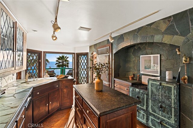 kitchen with a sink, dark countertops, dark wood-style flooring, and a kitchen island