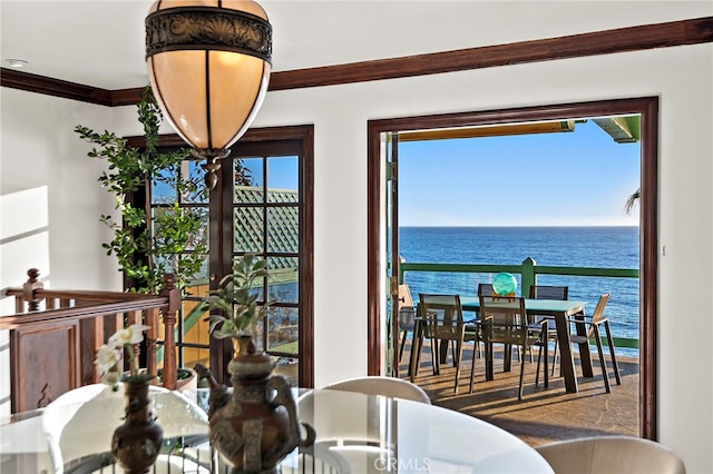 dining room with crown molding and a water view