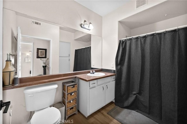 full bath featuring visible vents, toilet, vanity, and wood finished floors