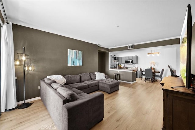 living room featuring light wood-type flooring, visible vents, and baseboards