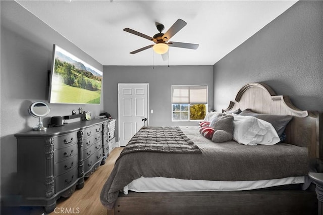 bedroom featuring light wood finished floors, ceiling fan, and a textured wall