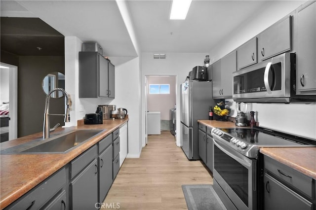 kitchen with a sink, gray cabinetry, and stainless steel appliances