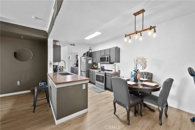 kitchen featuring a sink, stainless steel appliances, a breakfast bar, and light wood-style flooring