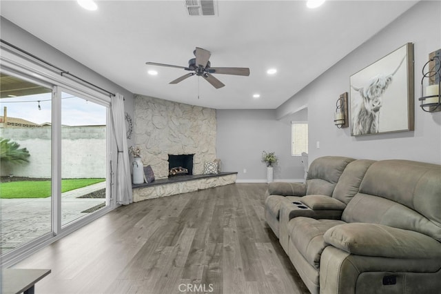 living room with visible vents, baseboards, recessed lighting, a fireplace, and wood finished floors