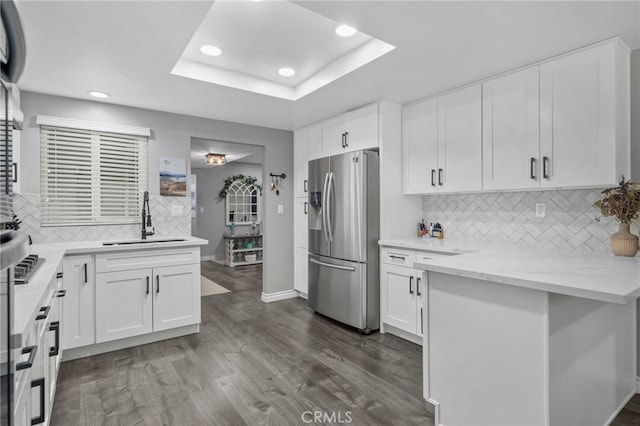 kitchen with a sink, dark wood-type flooring, stainless steel refrigerator with ice dispenser, white cabinetry, and a raised ceiling