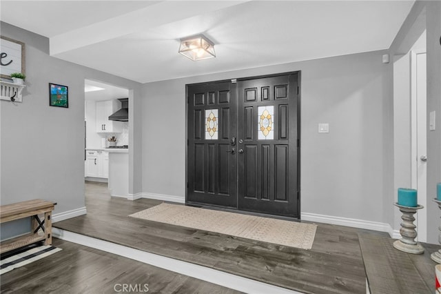 entryway with dark wood-type flooring and baseboards