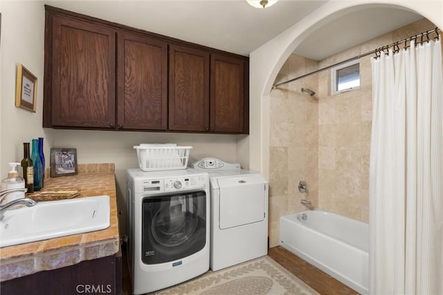 laundry area with arched walkways, laundry area, washer and dryer, and a sink