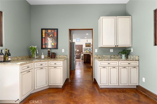 kitchen featuring a sink, concrete floors, and light stone countertops