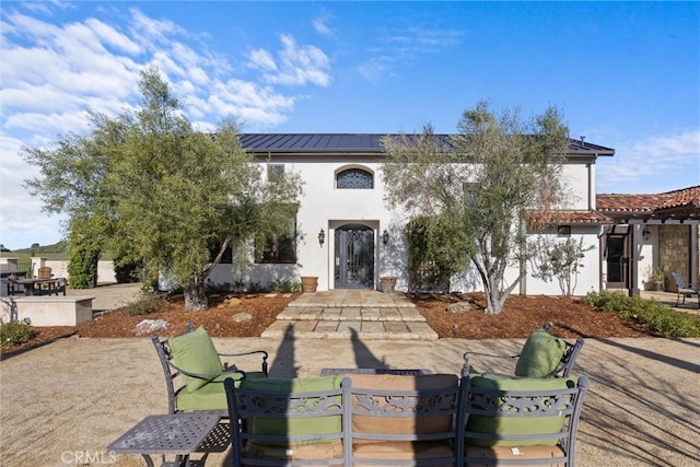 view of front of house featuring outdoor dining space, stucco siding, metal roof, and a patio