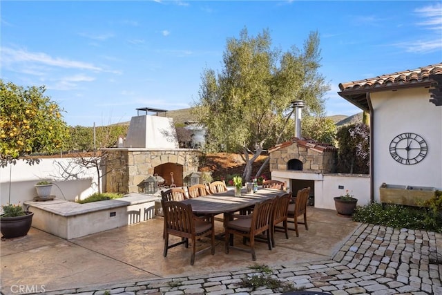 view of patio with outdoor dining area, fence, and an outdoor stone fireplace