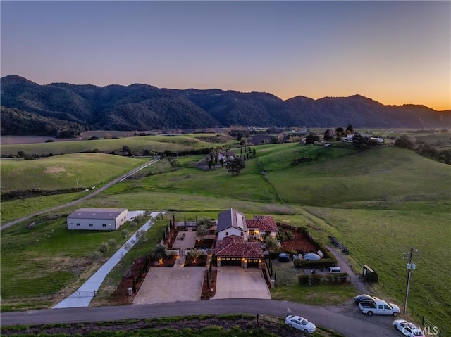 aerial view at dusk featuring a mountain view and a rural view