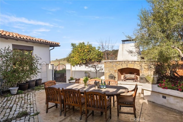 view of patio / terrace with outdoor dining area and an outdoor stone fireplace