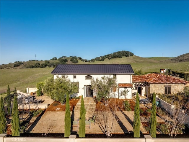 view of front of house featuring fence, stucco siding, a patio area, a mountain view, and metal roof