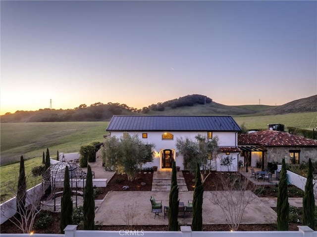 view of front of house with a patio, fence, a pergola, stucco siding, and metal roof